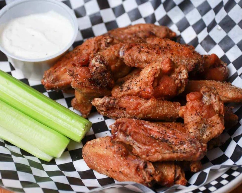 Crispy chicken wings tossed in sauce with carrots and celery at Monty's Pizza in Edmonton, AB